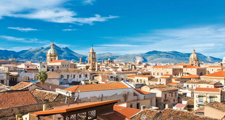 Panoramablick auf Palermo mit Bergen im Hintergrund unter blauem Himmel.