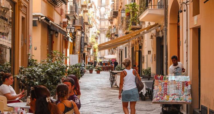Charmante Straße mit Tischen, Cafés und spazierenden Menschen.
