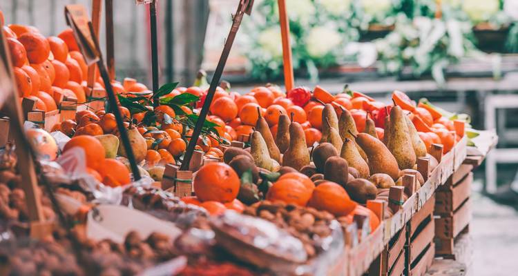 Vielfalt an frischen Früchten und Nüssen, die an Marktständen ausgestellt sind.