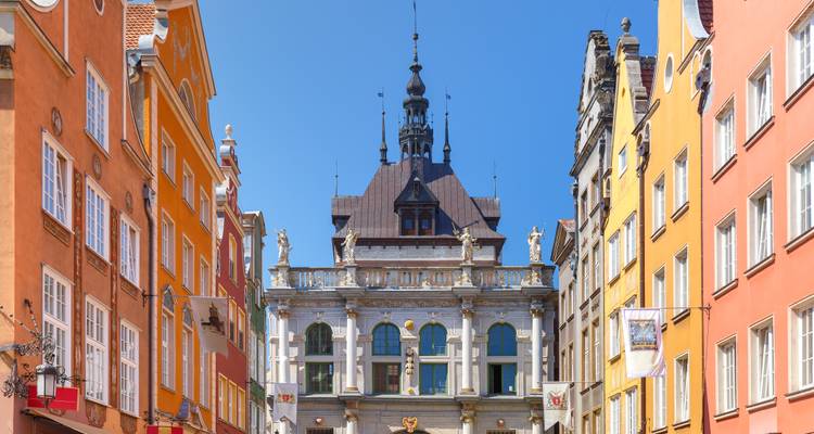 Farbenfrohe Fassaden säumen eine historische Straße, die zur kunstvollen Altstädter Rathaus in Danzig führt.