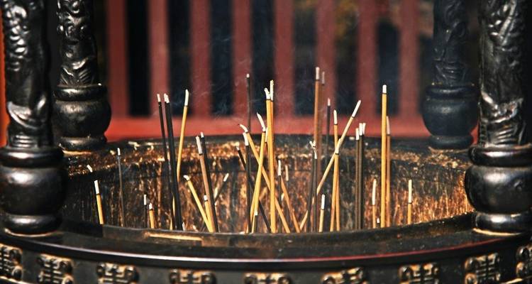 Incense sticks burning in a traditional holder, with smoke rising.