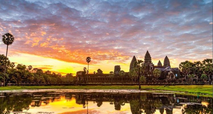 Ancient temple complex reflecting in water at sunset.
