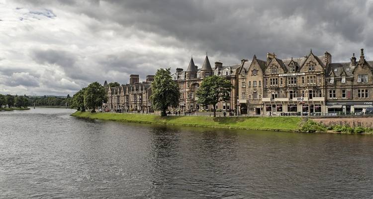 Stadsgezicht aan de rivier met historische gebouwen onder een bewolkte hemel