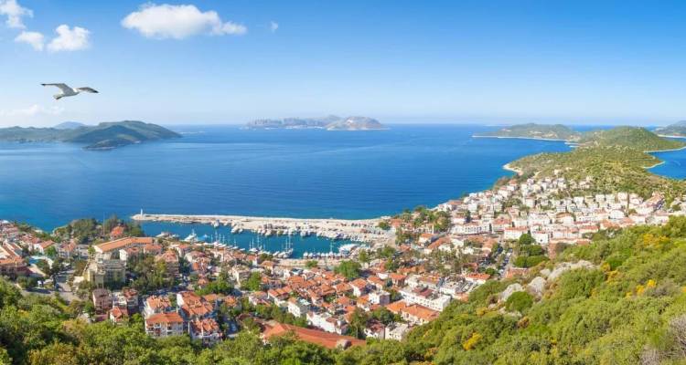 Panoramic view of Kas town’s white houses and marina beside vivid blue Mediterranean waters.
