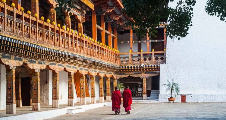 Monks walking through a beautifully ornate courtyard with colorful wooden architecture.