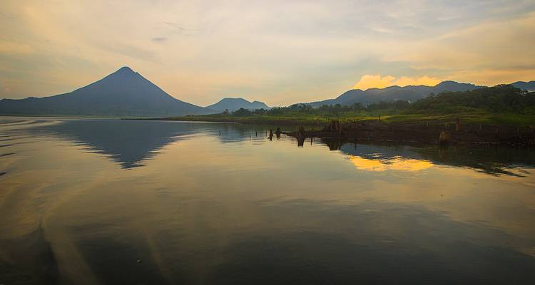 Cône volcanique et collines environnantes reflétés dans un lac calme au crépuscule