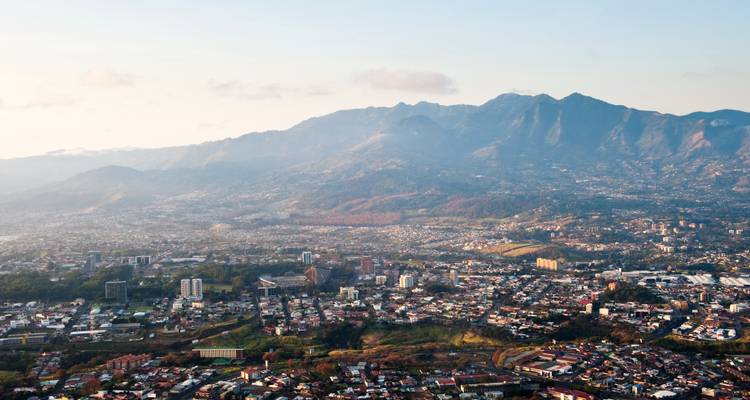 Vista aérea amplia de una ciudad extendida por el piso de un valle bajo montañas escarpadas.