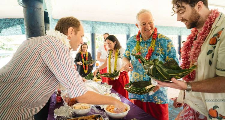 Guests receive traditional Samoan plates of food decorated with leis and colourful sarongs at a community feast.