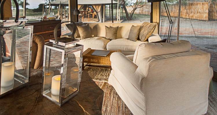 Gemütlicher Loungebereich in einem Zeltcamp mit Sitzgelegenheiten und Laternen.