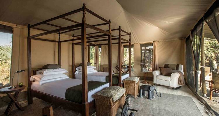 Innenraum eines luxuriösen Safari-Zeltes mit zwei Einzelbetten und Dekoration.