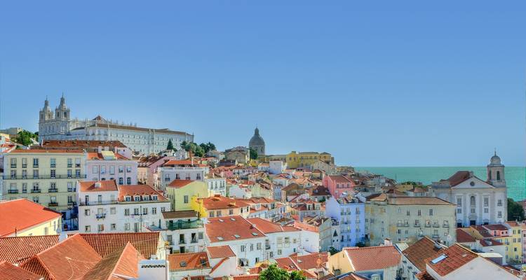 Panoramic view of a cityscape with colorful rooftops by the sea.