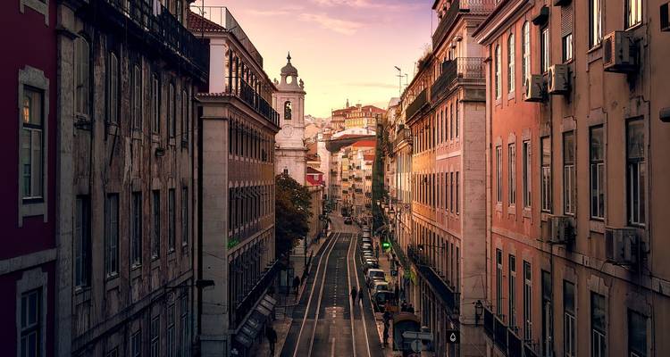 Narrow city street between historic buildings at sunset.