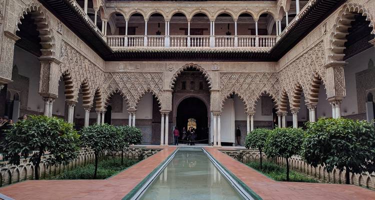 Ornate historic courtyard with arches and greenery.