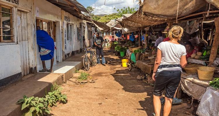 Des gens qui marchent dans un marché animé avec des étals et des bicyclettes.