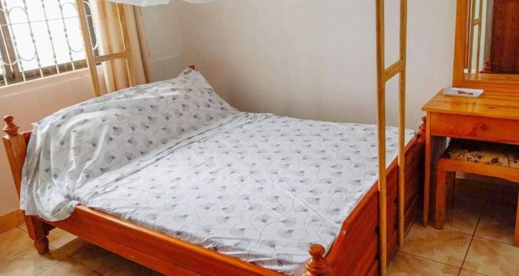 Chambre simple avec un lit et un bureau en bois.