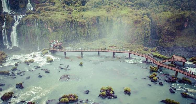 Los visitantes caminan por una pasarela elevada que se extiende hacia las ensordecedoras Cataratas del Iguazú.