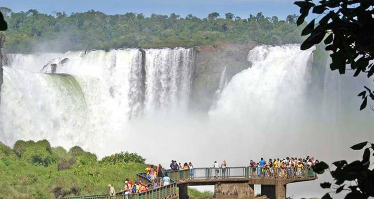 Menigten staan op een uitkijkplatform naast de kolkende Iguazu-watervallen, omgeven door nevel.