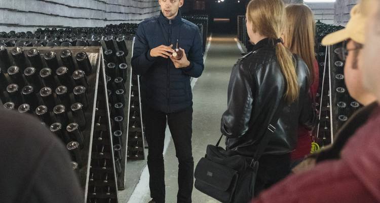 Innenraum einer Kellerei oder eines Kellers mit Menschen und Regalen voller Flaschen.