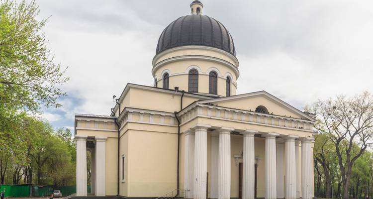 Neoklassizistische Kirche mit einer Kuppel und Säulen, umgeben von Bäumen.