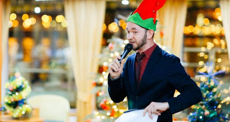 Hombre con gorro de duende hablando por un micrófono.