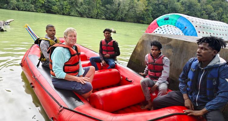 Fünf Personen sitzen in einem roten Schlauchboot auf einem See.