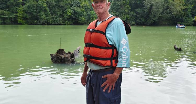 Mann, der am See steht und eine Schwimmweste trägt.