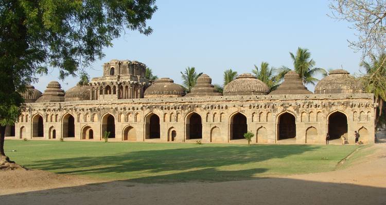 Long temple with domed roofs surrounded by a grassy courtyard.