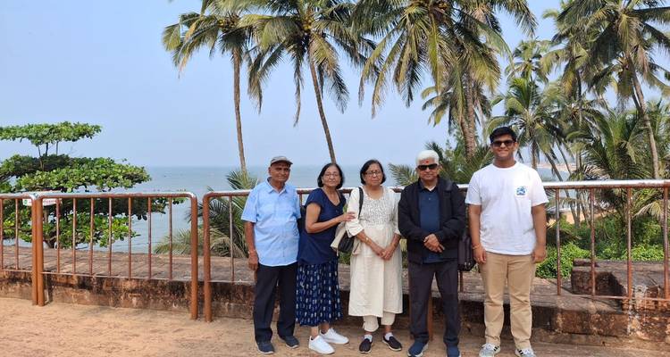 Group of older adults standing in front of palm trees and a beach view.