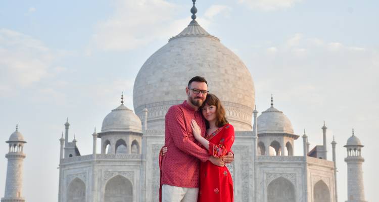 Portrait of couple in front of Taj Mahal’s main dome during soft morning light.