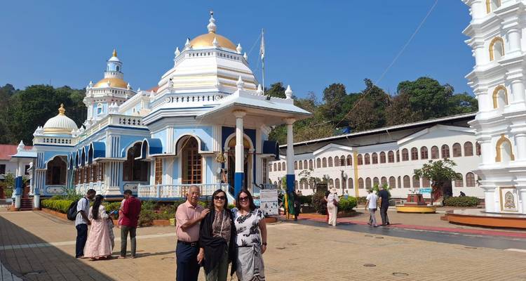 Group of people posing in front of a temple with blue and white architecture.