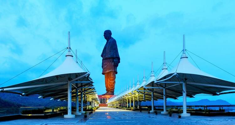 Statue avec une rangée de parapluies au crépuscule, créant une composition symétrique.