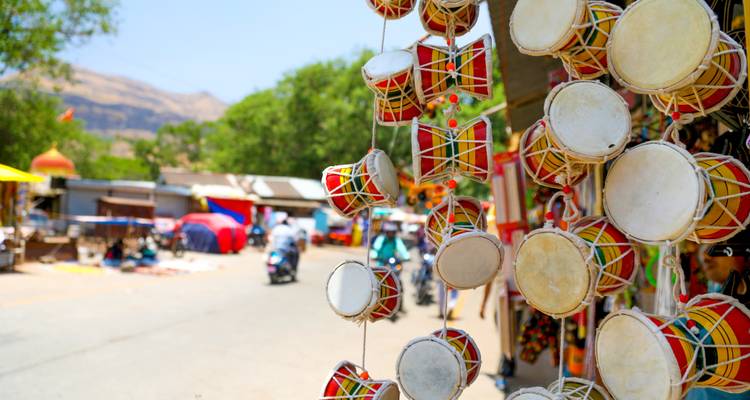 Reihe bunter Trommeln, die auf einem Marktplatz hängen, mit unscharfem Hintergrund.