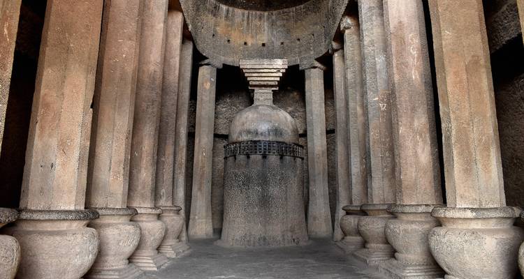 Interior of a historic cave with stone columns and an ancient structure.