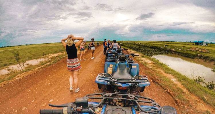 Les aventuriers lors d'une excursion en quad ATV le long d'une piste de terre rouge à travers la campagne cambodgienne