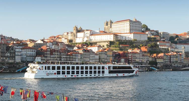 Bateau de croisière fluviale sur une rivière pittoresque avec une ville historique en arrière-plan.