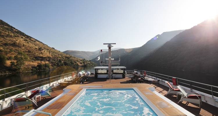 Vue depuis le pont d'un bateau de croisière avec un jacuzzi et des chaises longues.