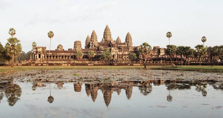 Wide view of Angkor Wat with reflection in water.