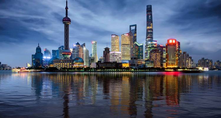 Iconic neon-lit skyline of Shanghai reflected in the Huangpu River at night.