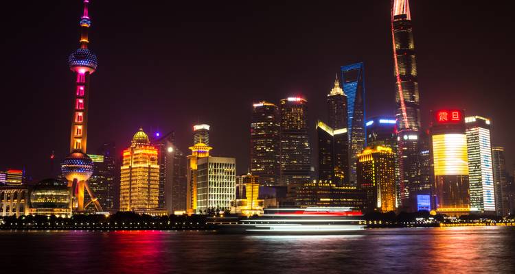 Shanghai’s futuristic skyline glowing with neon lights reflected in the Huangpu River at night.