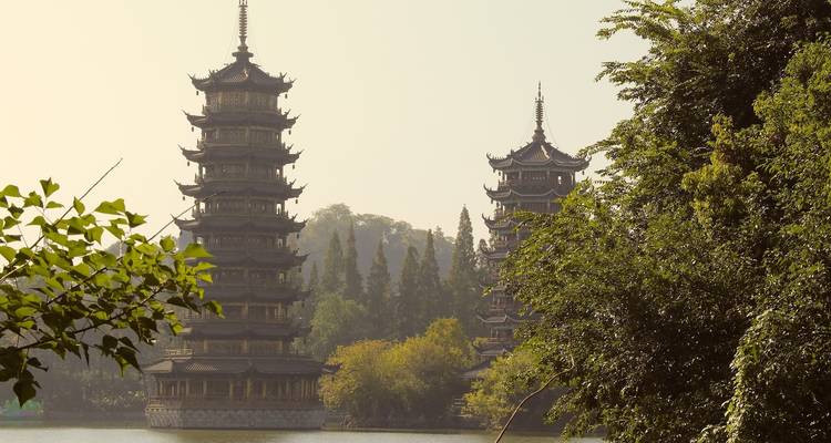 Pagodas gemelas reflejadas en un lago rodeado de exuberante vegetación.