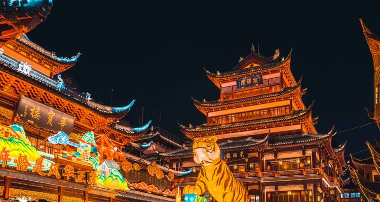 Edificios iluminados con faroles vibrantes y una gran decoración de tigre iluminan un bazar chino tradicional por la noche.