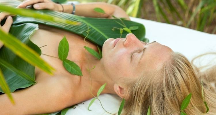 Person lying down covered with leaves for a spa treatment.