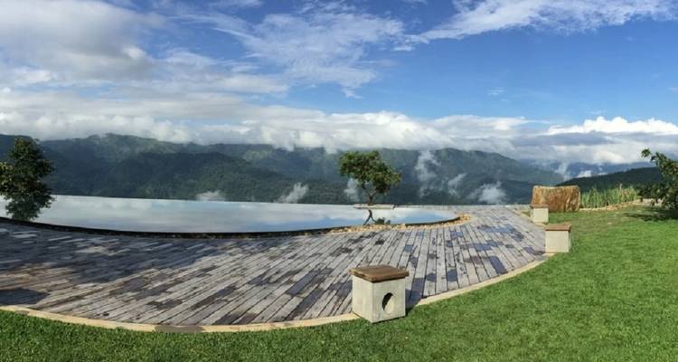 Scenic view of a mountainside with clouds and a wooden terrace.