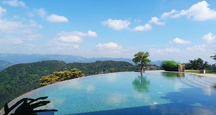 Infinity pool overlooking lush green hills.