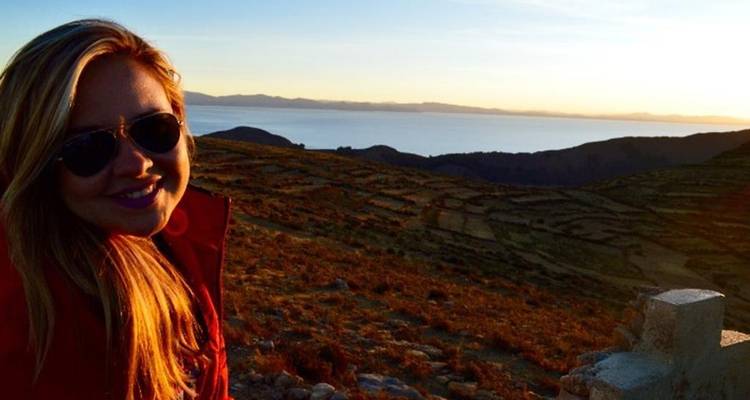 Femme souriante portant des lunettes de soleil savourant les vues du coucher de soleil sur les collines en terrasses près du lac Titicaca.