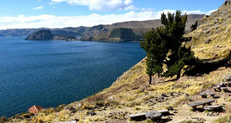 Las laderas de la colina seca y polvorienta descienden abruptamente hacia las aguas azules y expansivas del Lago Titicaca.