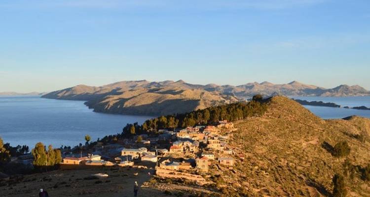 Le petit village perché sur la colline surplombe les eaux scintillantes et les îles du lac Titicaca à l'heure dorée.
