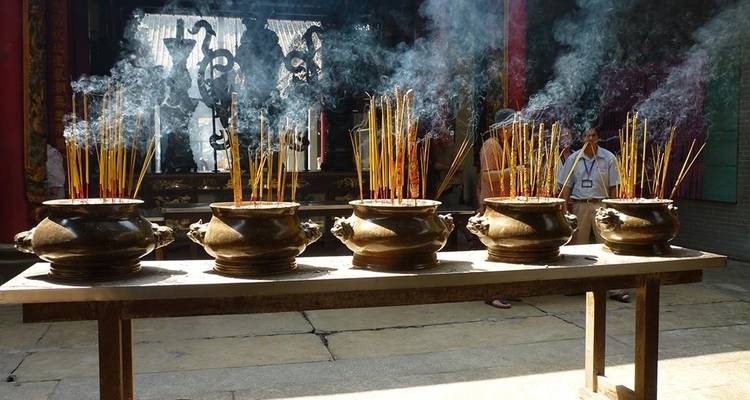 Rows of incense burn in bronze urns filling a Saigon temple with swirling smoke.