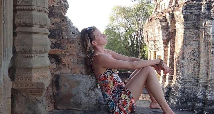 Traveler relaxes against ancient stonework of an Angkor temple bathed in late-day light.