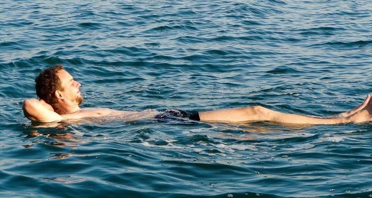 Mann treibt gemütlich in einem Gewässer.